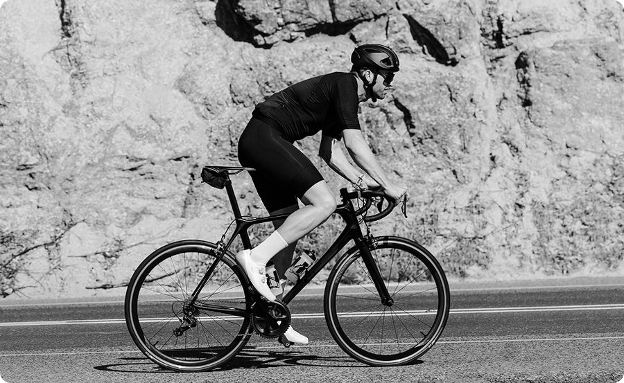 Person riding a bicycle on a road with a rocky cliff in the background
