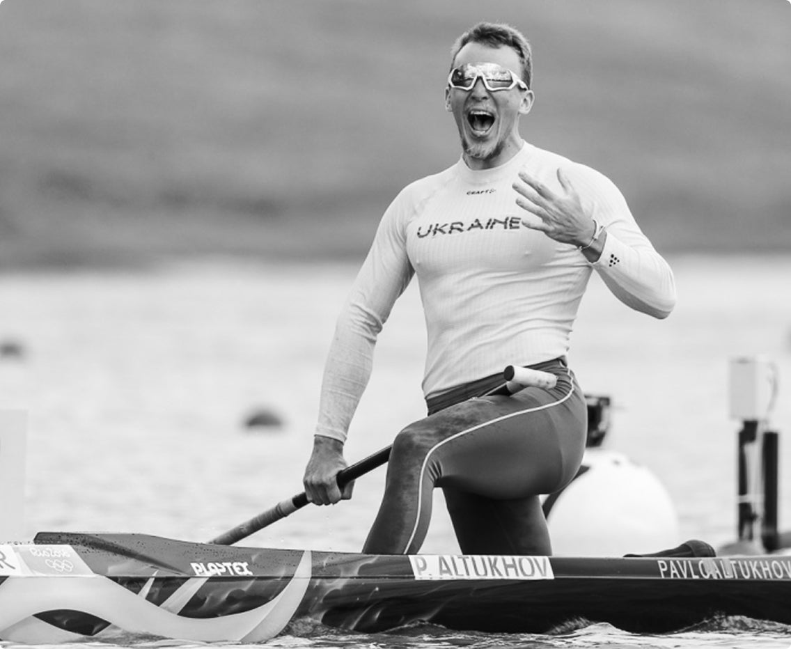 Man in a kayak with 'Ukraine' on his shirt, celebrating on water.