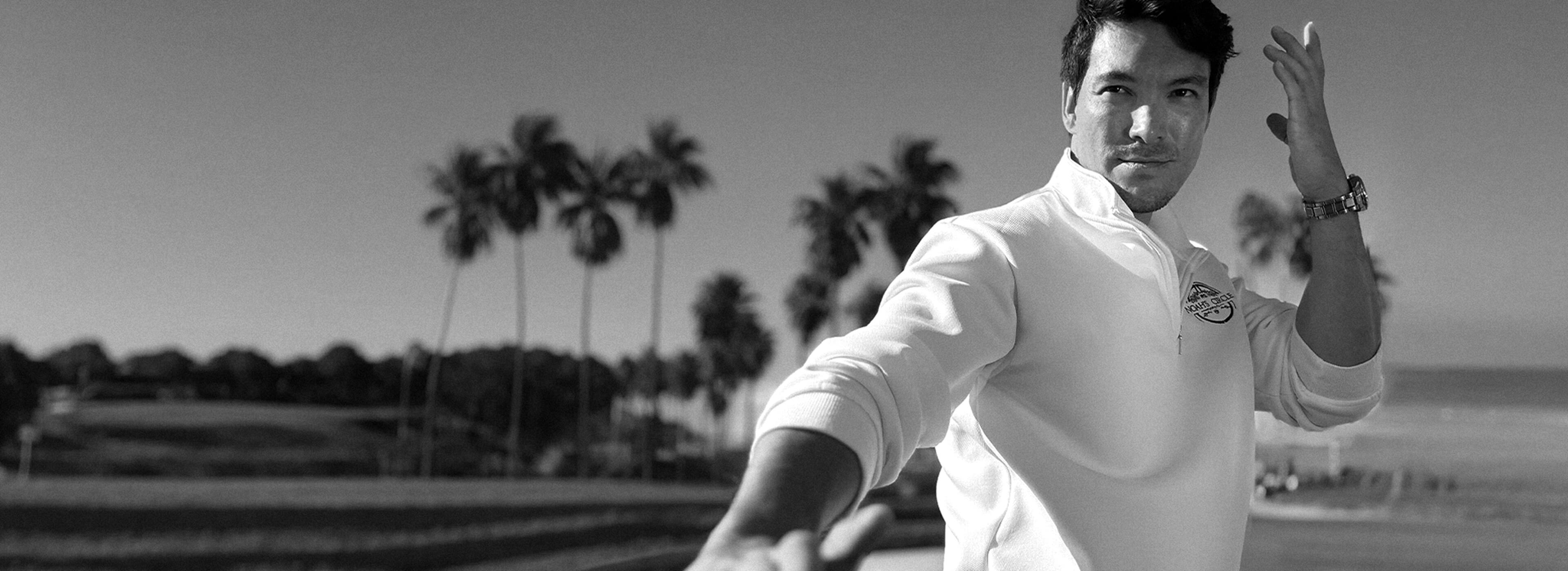Man in a white shirt with a palm tree background