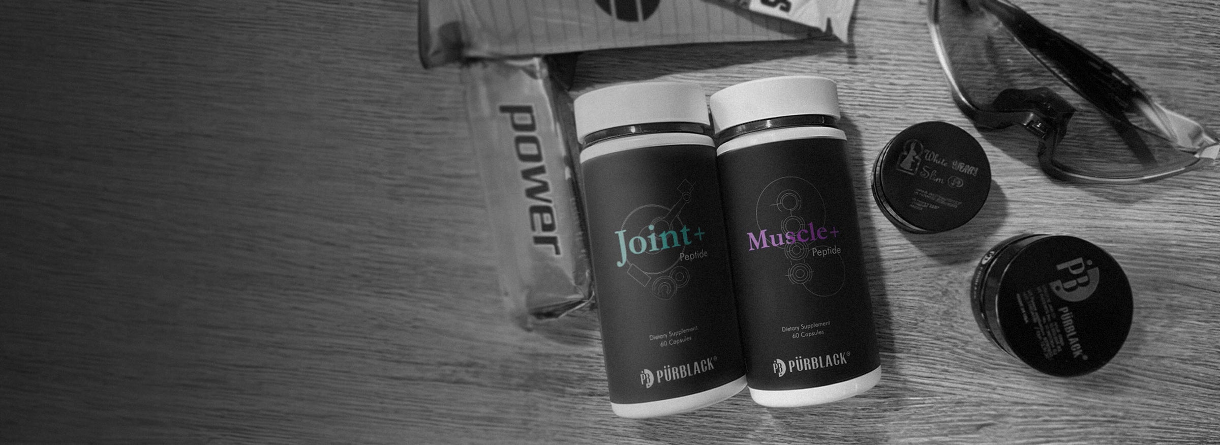 Two black containers labeled 'Power' and 'Muscle' on a wooden surface.