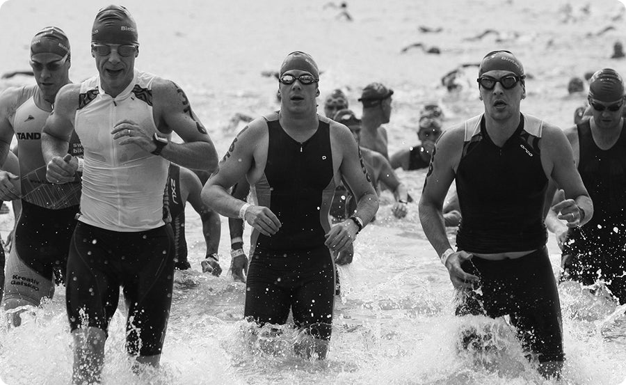Black and white photo of swimmers in a triathlon transitioning from water to陆地