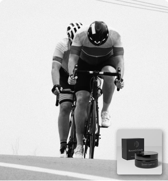 Two cyclists racing on a road with a product display of 'Nourish' cream and balm.