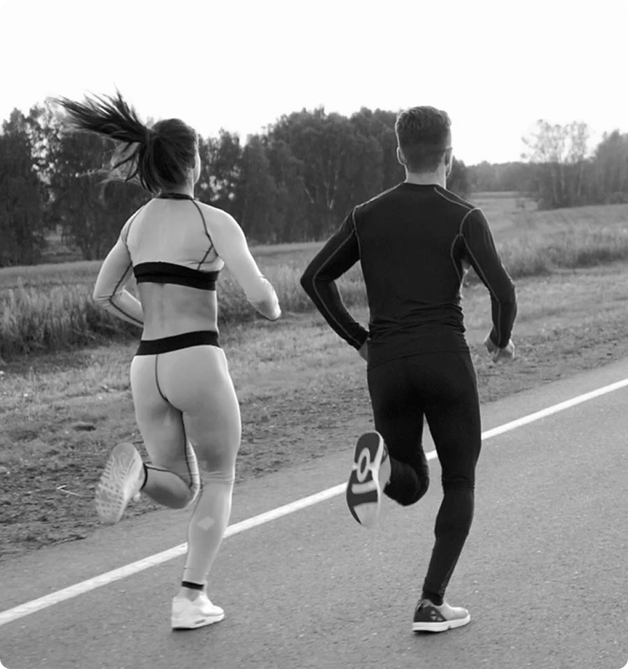 Two people running on a road with a natural landscape in the background