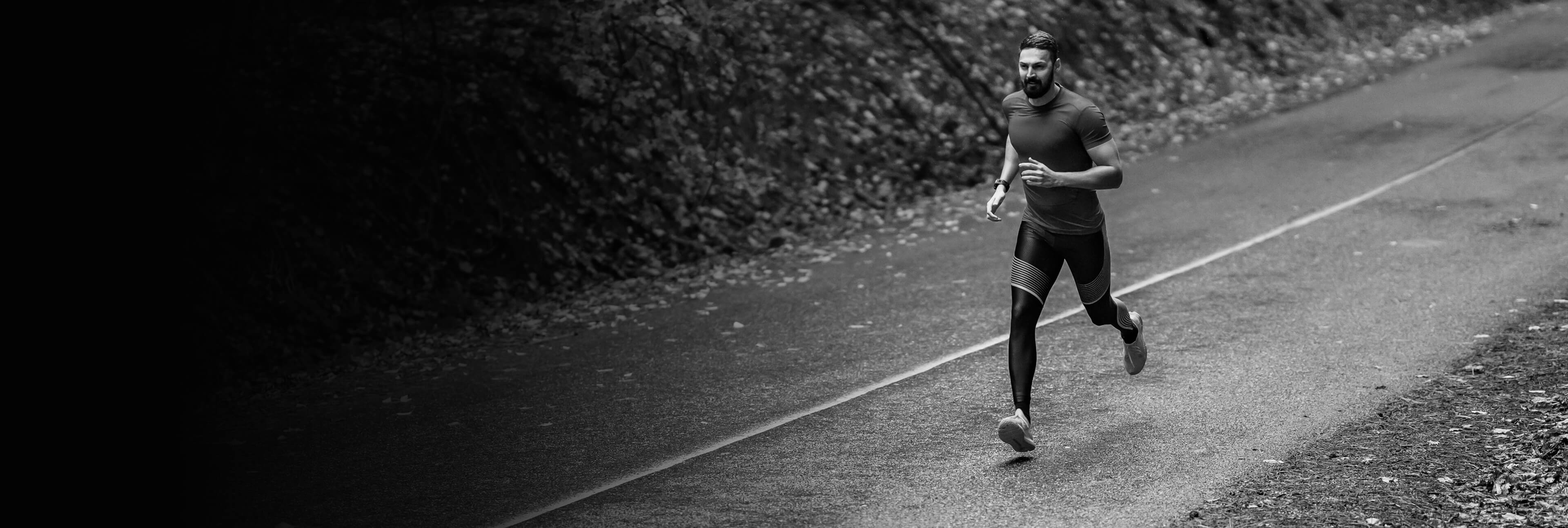 Man running on a road with a natural, possibly forested, background